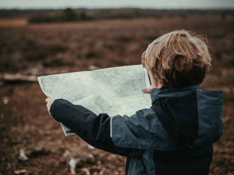 A boy reading a map, where the different routes represent the many ways this blog can help navigate healing from trauma.