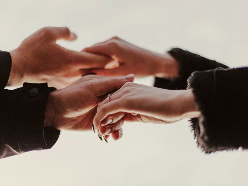 Two people holding hands representing the feelings of never being alone.