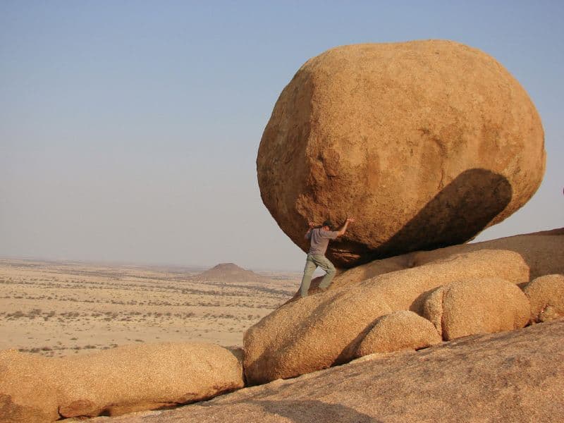 Man pushing boulder representing the strength, power, and confidence that therapy can bring.