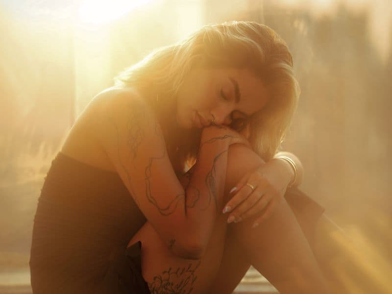 Woman with eyes closed representing reflection of trauma and self-blame.