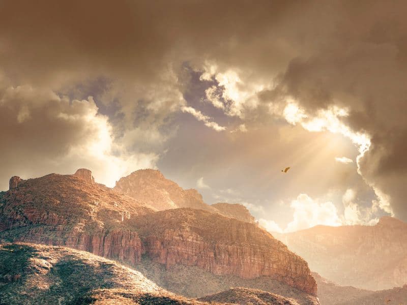 Light shining through clouds onto mountains representing hope, comfort, and a sense of calm.