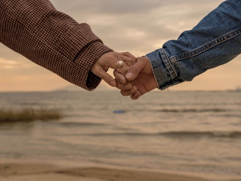 Holding hands at the beach to prove comfort.