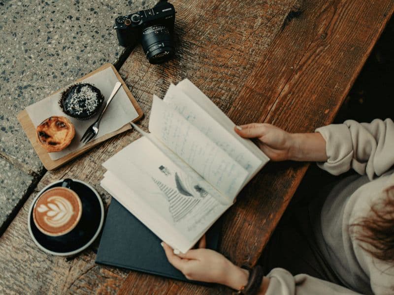 Person looking through a journal with a camera in place ready to creatively express themselves by taking pictures.