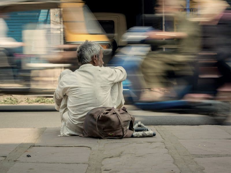 Man sitting down and reflecting as vehicles are blurred as they speed by, representing detachment of feelings.