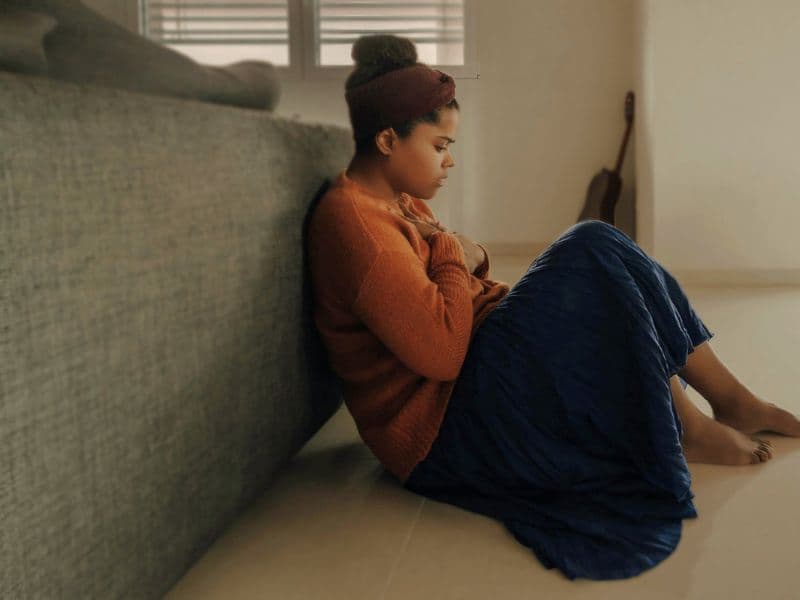 Girl sitting on floor looking upset, representing the guilt of hurting a loved one by setting boundaries.