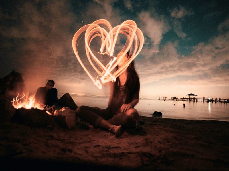 Woman drawing a heart in the air representing self-love.