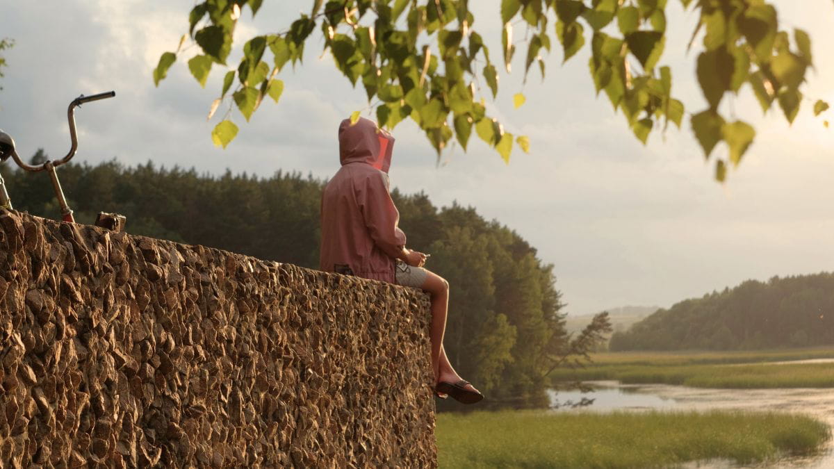 Person sitting on the edge of a cliff appearing to be reflecting, representing thoughts of guilt after abuse.