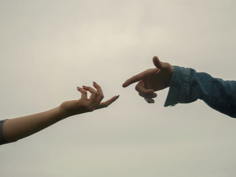 Two hands reaching toward each other, symbolizing emotional distance, connection struggles, and the effects of childhood trauma in relationships.