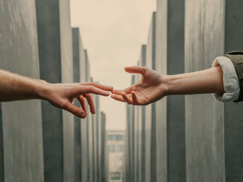 Two hands reaching for each other representing the importance of support when healing from abuse.