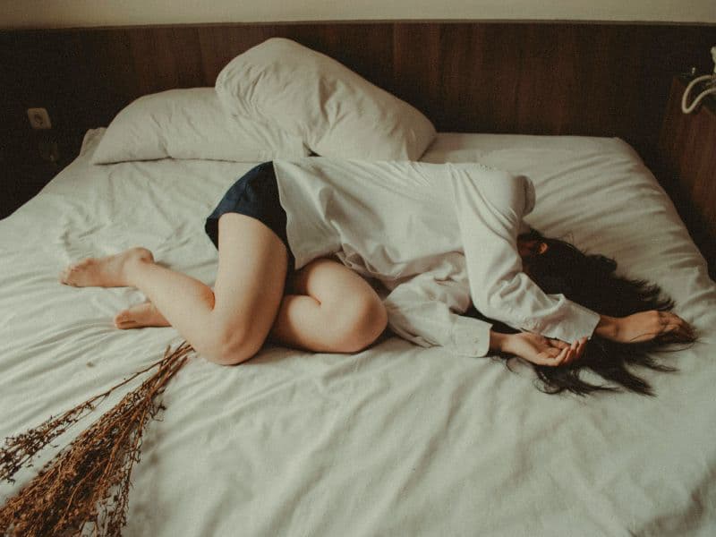 Girl lying on bed appearing to be in distress.