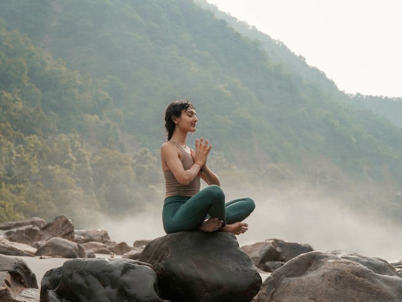 Person meditating outdoors while practicing grounding techniques for anxiety relief.
