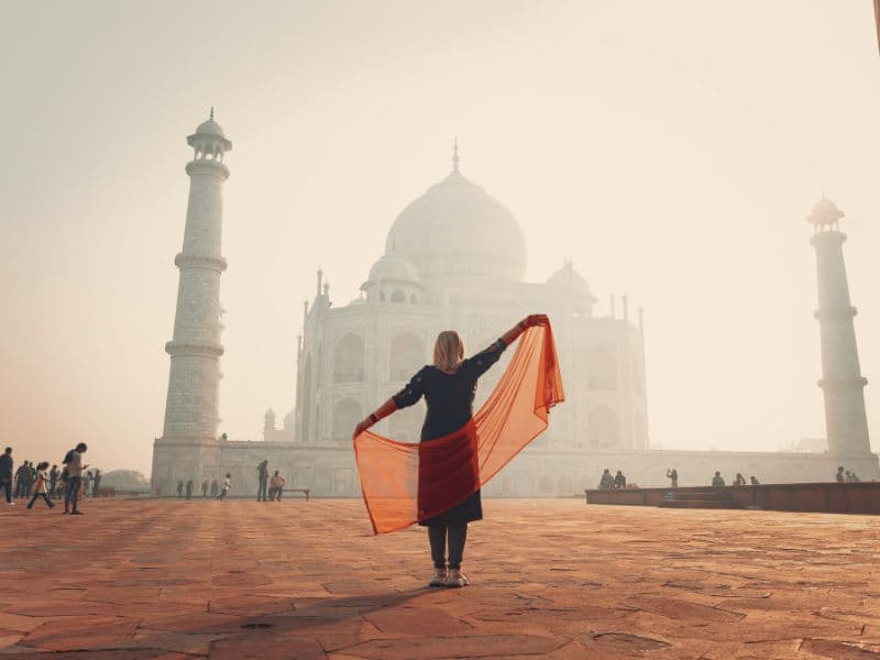 Woman in traditional clothing facing the Taj Mahal at sunrise, representing hope, healing, and positive change around mental health.