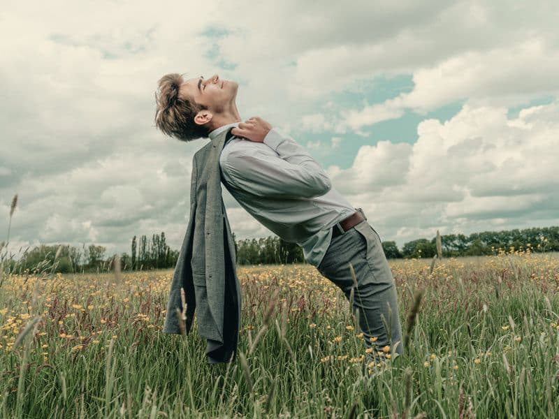 Man standing in an open field looking toward the sky, symbolizing healing, self-awareness, and recovery from hidden trauma.