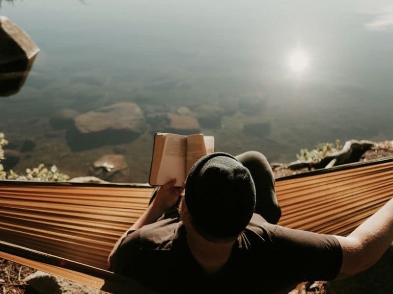 Person relaxing in a hammock while reading a book, reflecting on the journey of healing without therapy.