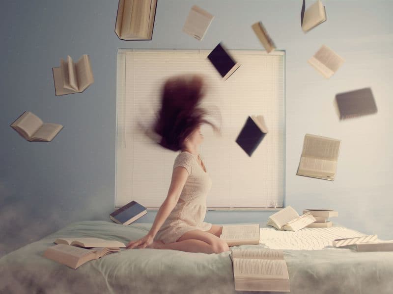 Overwhelmed woman surrounded by books illustrating the mental load and pressure often experienced by high-functioning adults with unresolved trauma.