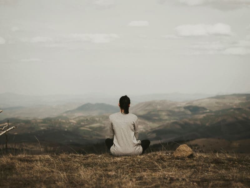 Person sitting on grass while using grounding techniques to calm anxiety.