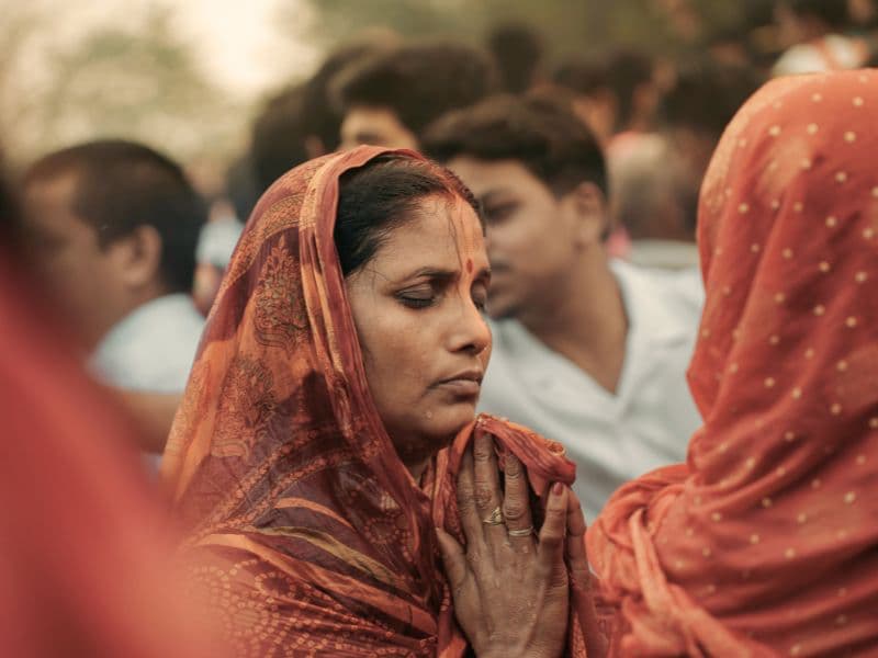 South Asian woman in traditional clothing with eyes closed in prayer, reflecting emotional struggles and mental health challenges.