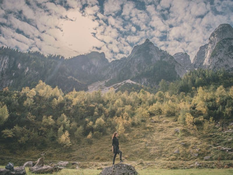 Woman standing on a mountaintop surrounded by nature, representing growth, resilience, and healing from childhood trauma.