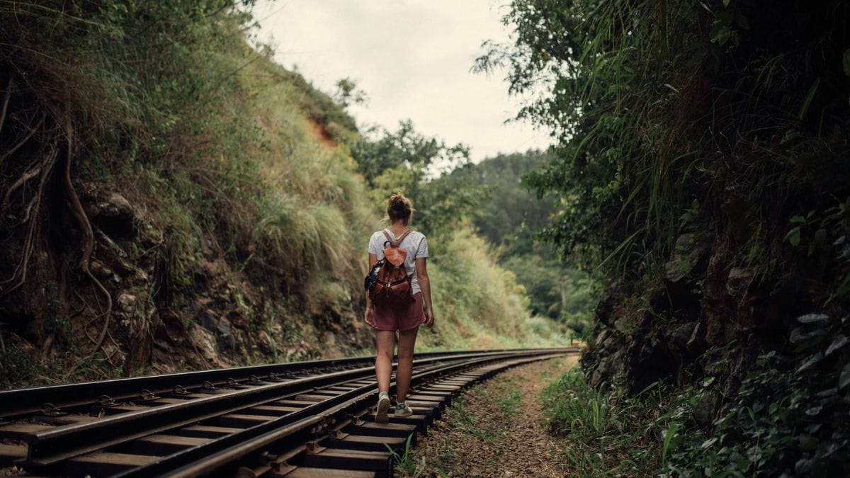 Woman walking alone on railway tracks through a forest, symbolizing the grief that can emerge during emotional healing.