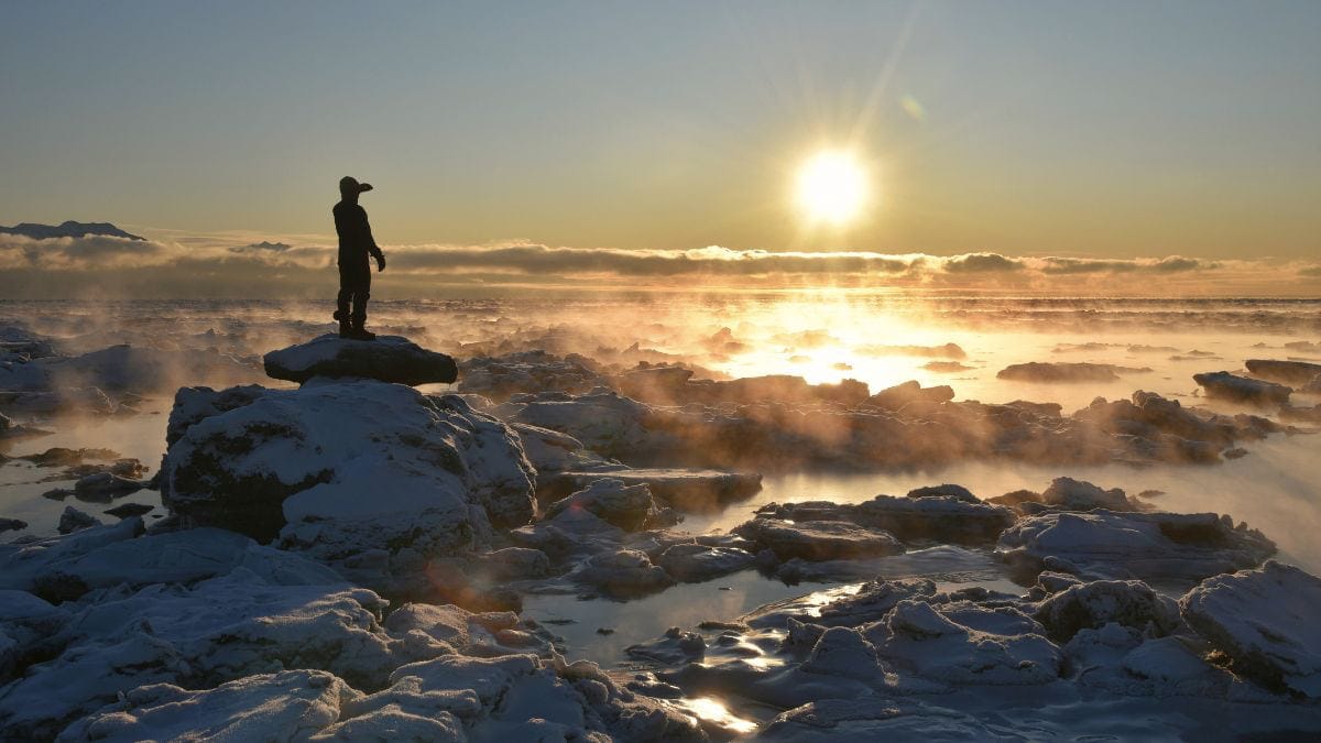 Person standing on a large rock above the clouds at sunrise, reflecting on healing from childhood trauma and living in survival mode.
