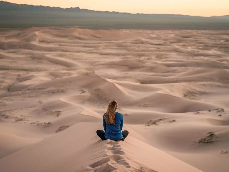 Woman sitting alone in the desert, representing the shame and isolation that can follow childhood abuse.