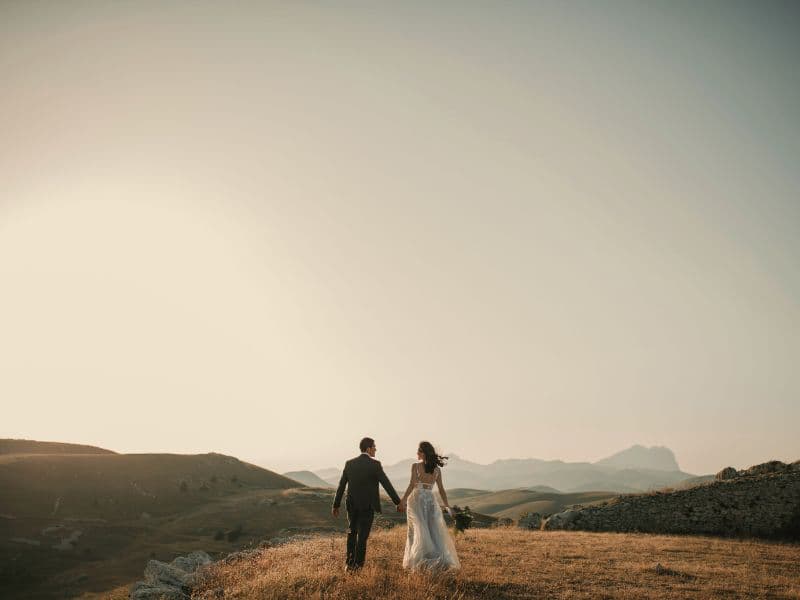 Man and woman holding hands while walking in nature.