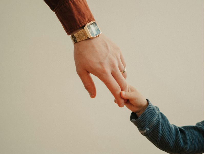 Adult gently holding a child's hand, representing safety, support, and healing from childhood trauma.