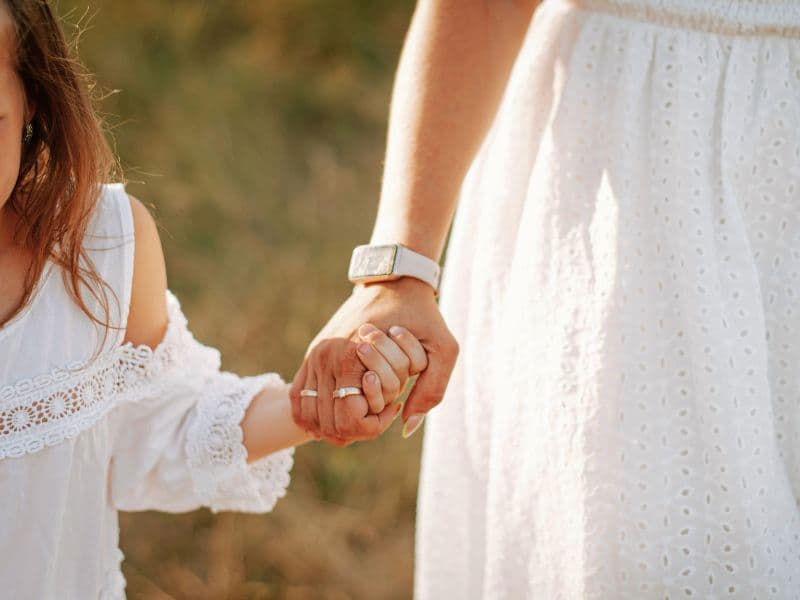 Little girl holding her mother's hand while walking.