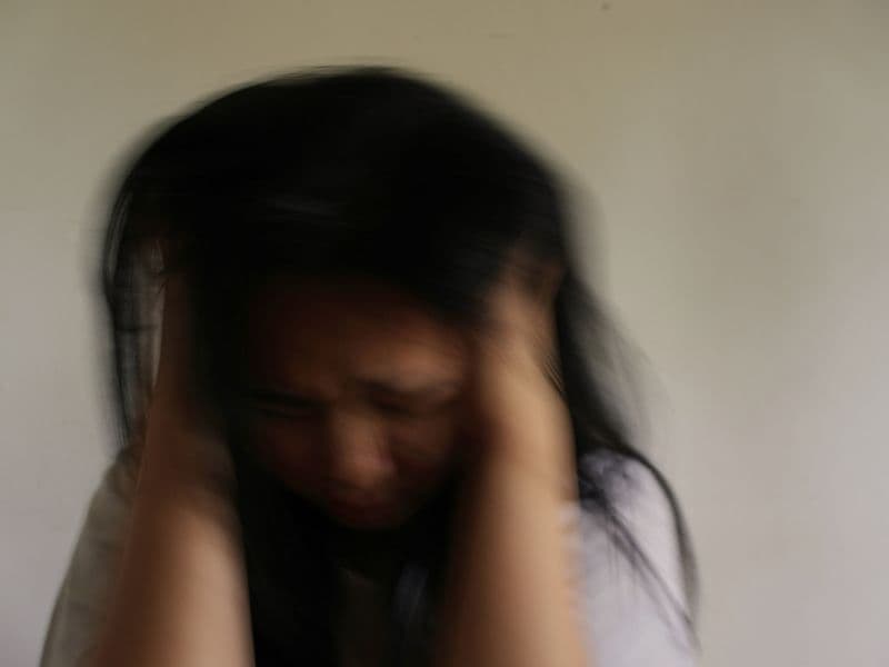 Woman holding her head with a blurred background.